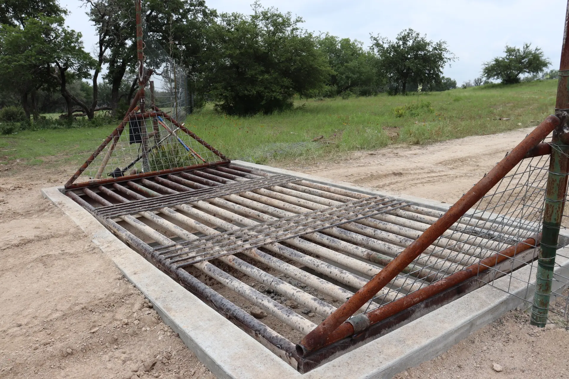 Custom welded steel pipe cattle guard installed across a ranch entrance road