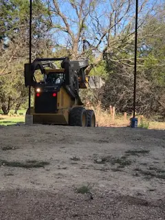 Skid steer working brush and dirt during a land clearing job on a Burnet County property