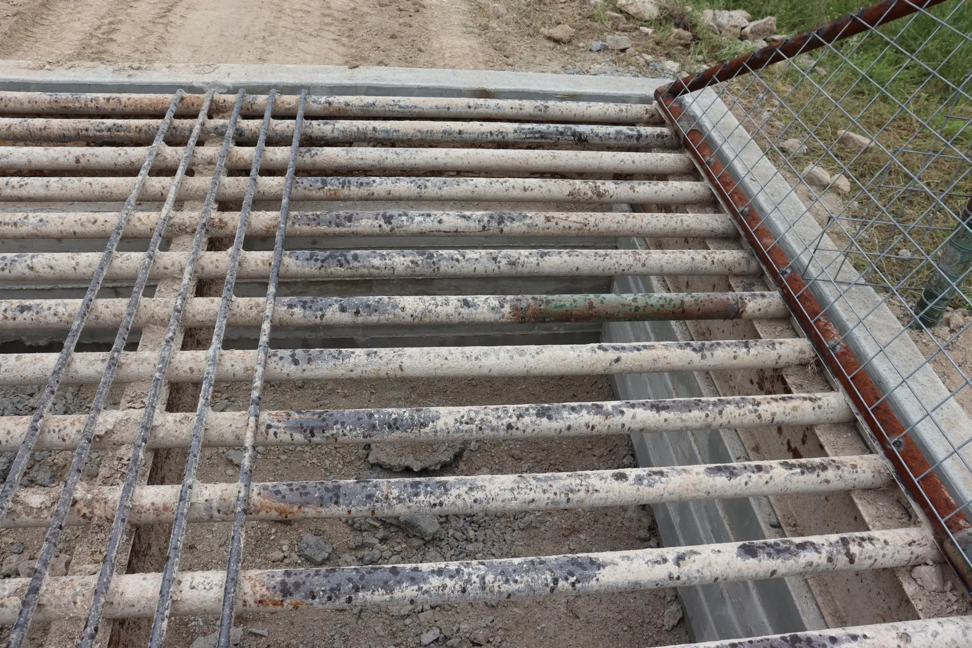 Close-up of hand-welded steel pipe cattle guard set in concrete